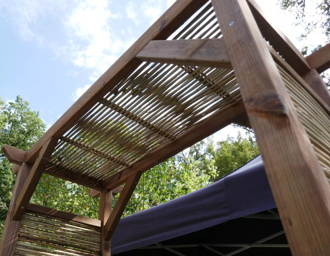 Arche de jardin en bambou et bois, structure artisanale française légère avec poutres et lattes, vue en extérieur sous un ciel bleu.
