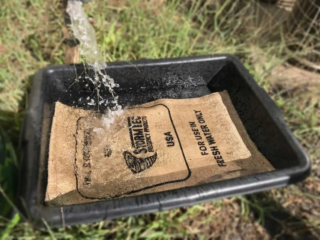 Sac anti-inondation Stormbag déployé dans un bac, libérant de l’eau pour l’arrosage du jardin.