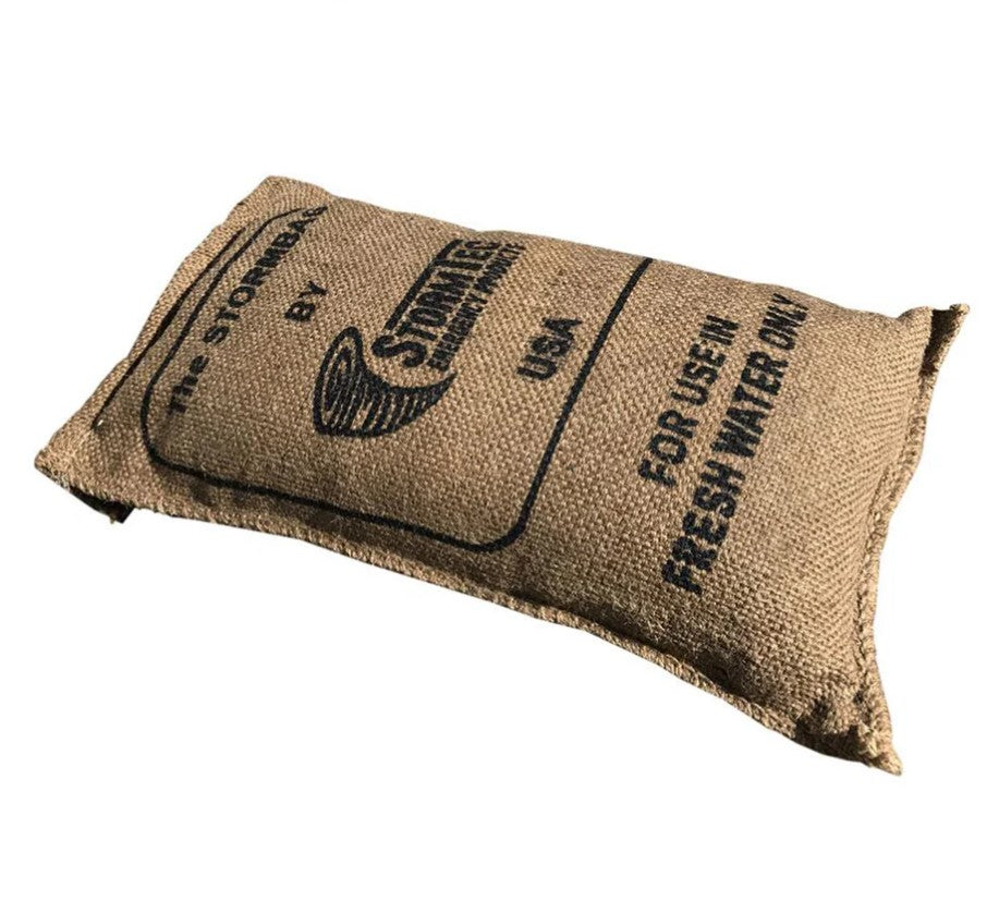 Sac anti-inondation en jute, plié, affichant le logo Stormbag et les mentions “For users … rain water pump” sur une surface naturelle.